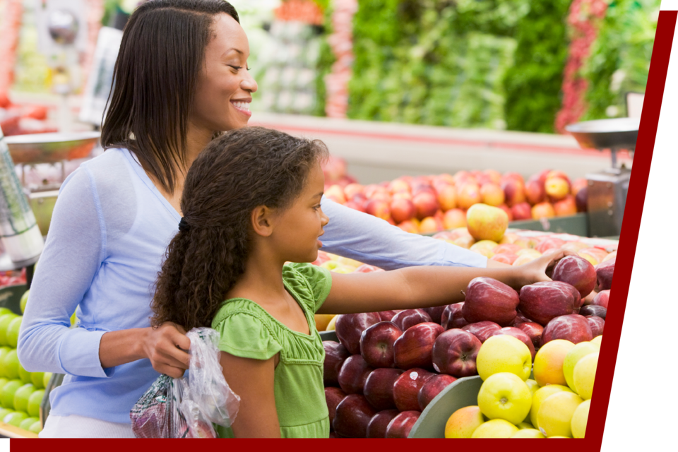 Mother and daughter selecting apples at a grocery store.